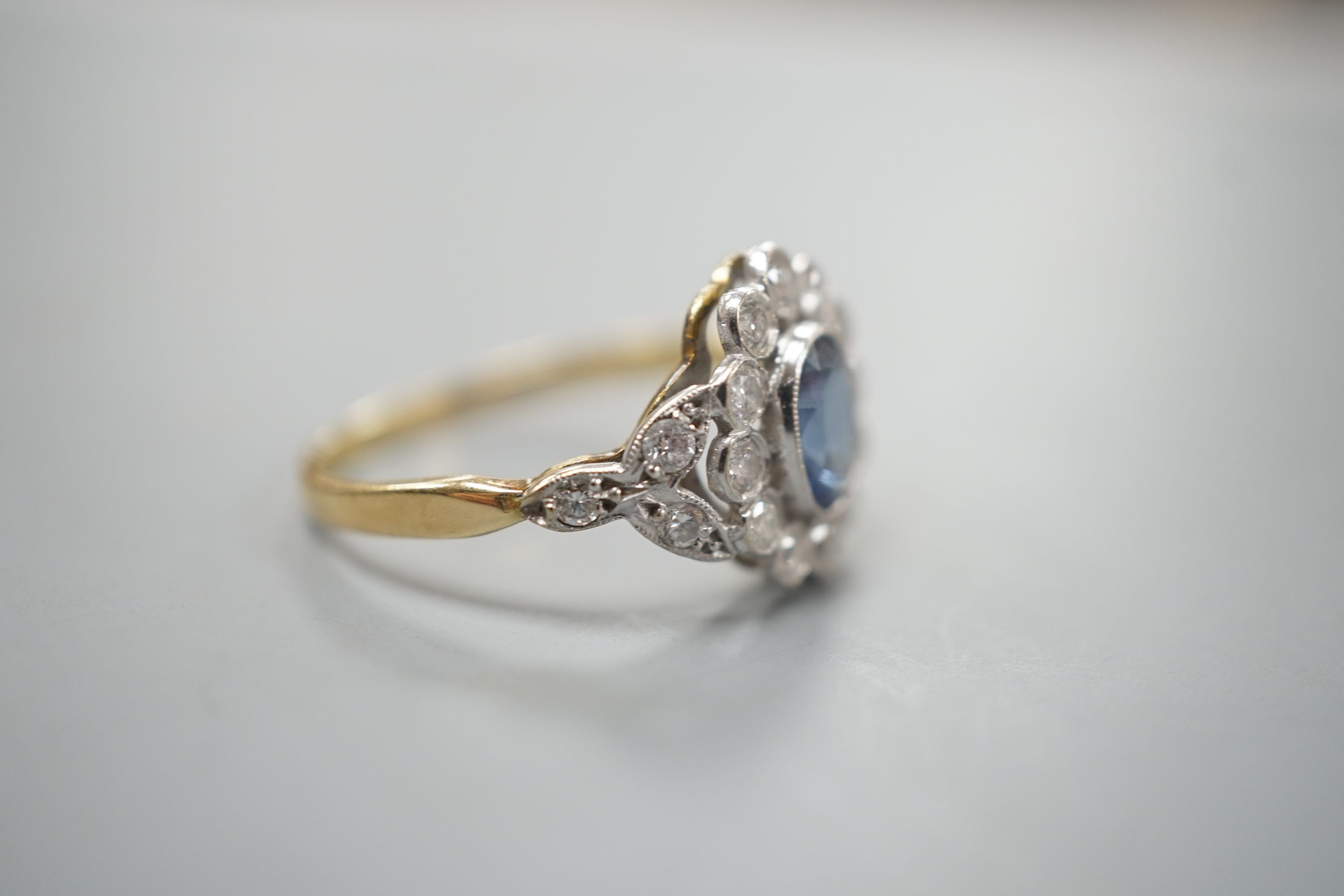 A yellow metal, sapphire and diamond set oval cluster ring, size T, gross weight 3.8 grams.